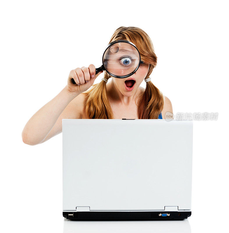 OMG !十几岁的女孩用放大镜惊讶于笔记本电脑的图像